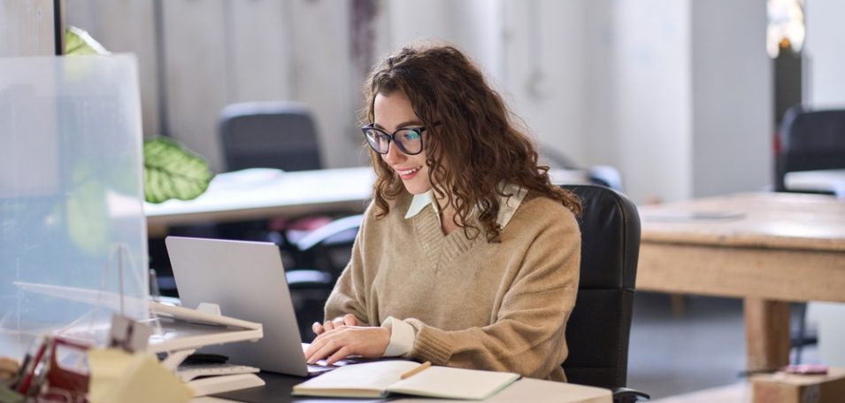 woman sitting at desk accessing her enterprise learning management system